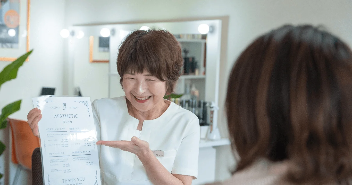 エステティシャンがメニュー表を顧客に見せている写真