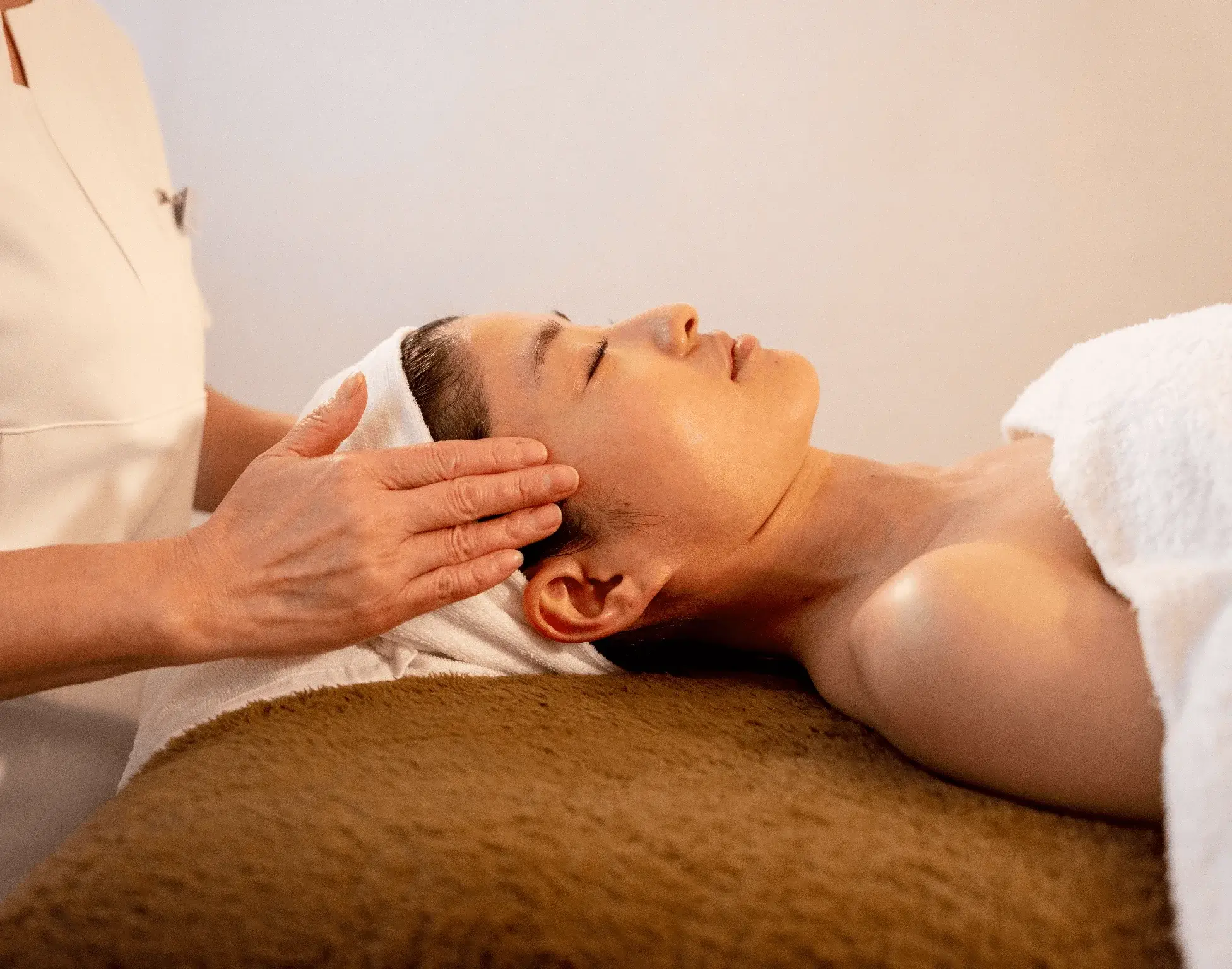 頭にタオルを被った女性がエステで施術を受けている写真